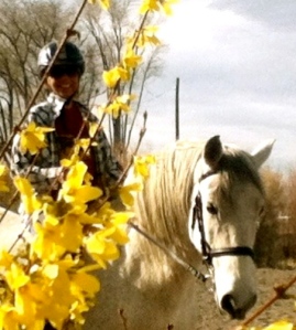Photo of Cheri on her horse Monarch behind flowers